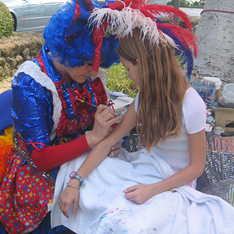 A young girl getting her painted by a clown. A young girl getting her painted by a clown.