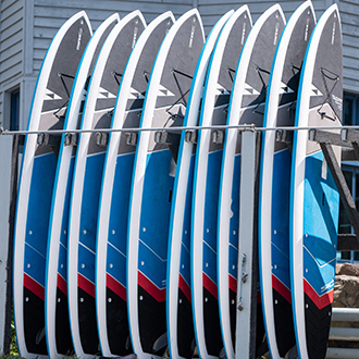 A group of paddleboards standing up-right in some racks. A group of paddleboards standing up-right in some racks.