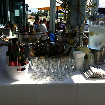 An array  of beers and wines with glasses on a table at shoreline lake